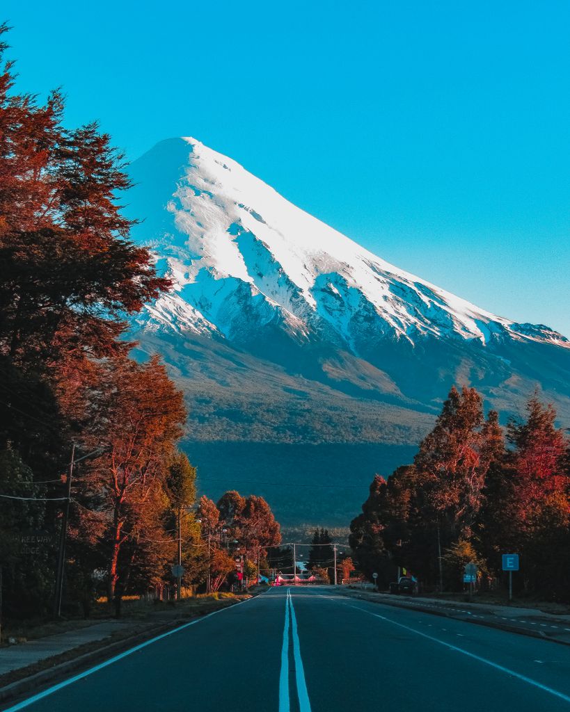 A breathtaking view of Osorno Volcano with a clear blue sky seen from a quiet road in Ensenada, Chile.