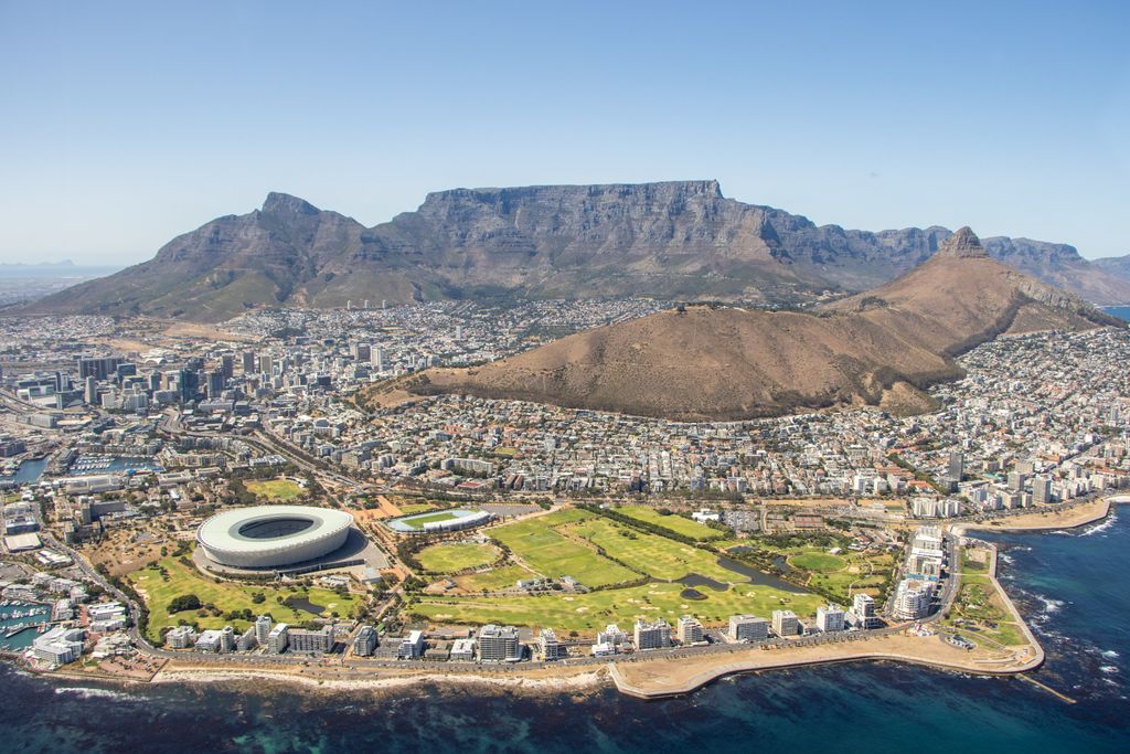 Breathtaking aerial shot of Cape Town, showcasing Table Mountain, cityscape, and stadium by the sea.
