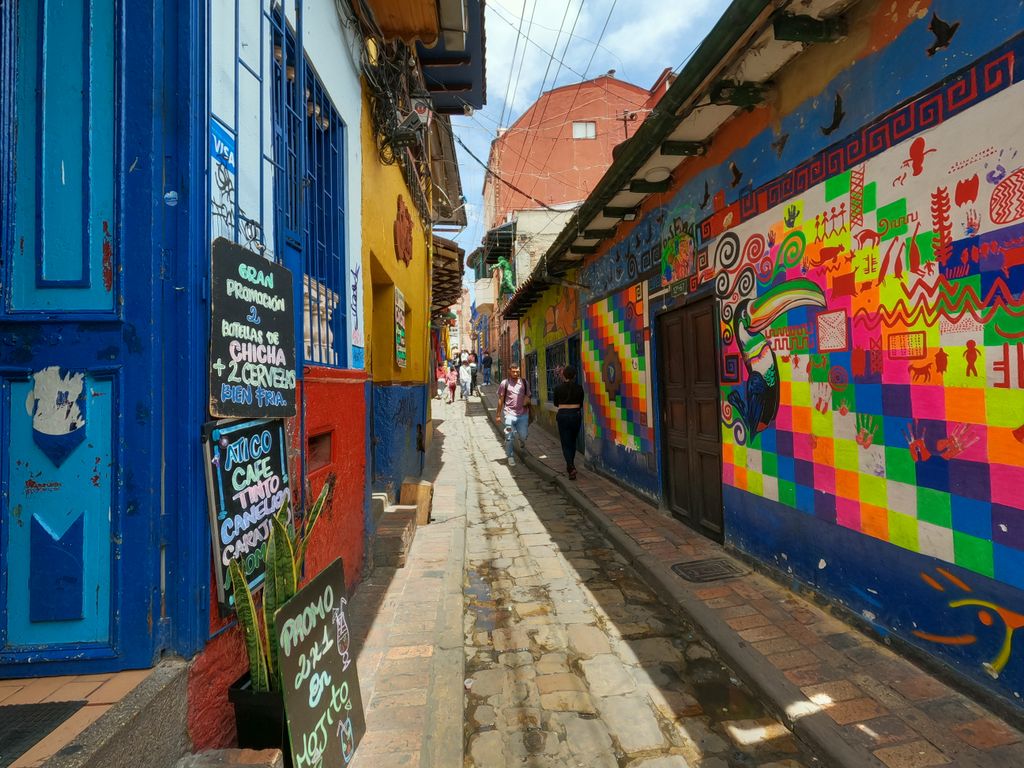 Colorful graffiti brightens a narrow alley in Bogotá, showcasing vibrant street art and lively urban culture.