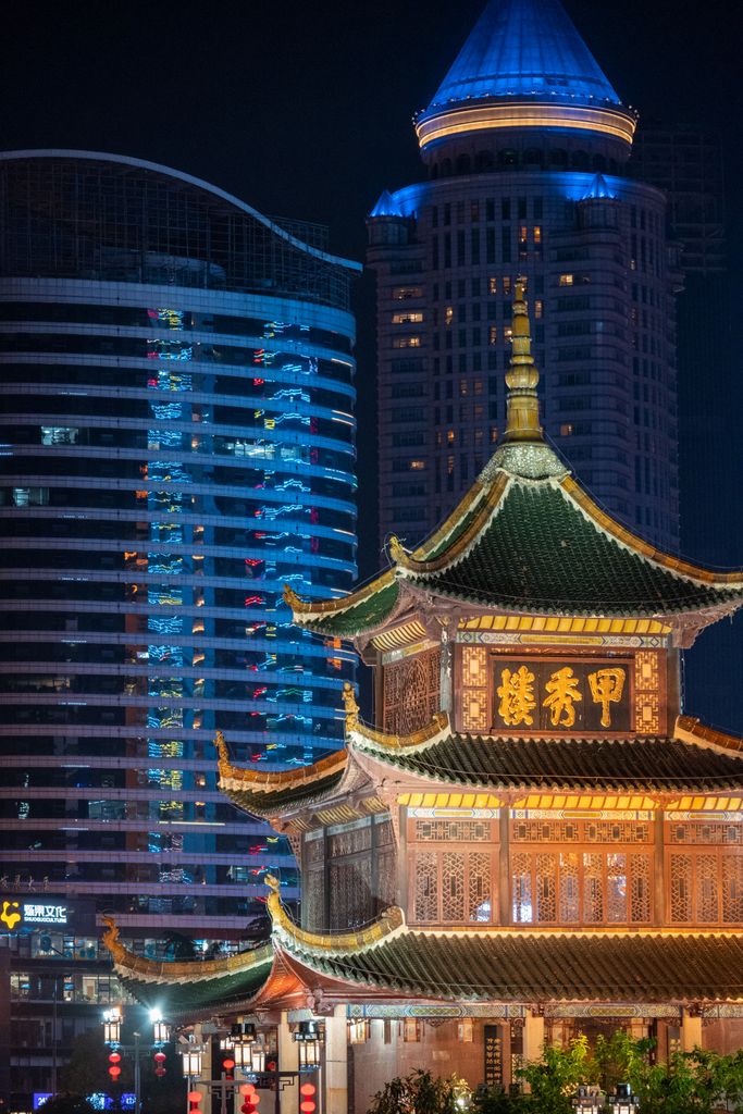 Traditional Jiaxiu Tower illuminated against the modern cityscape at night, showcasing architectural contrast.
