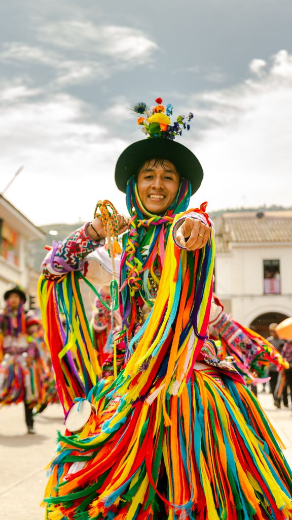 Vibrant traditional dance in a Peruvian square with colorful costumes and cheerful people.
