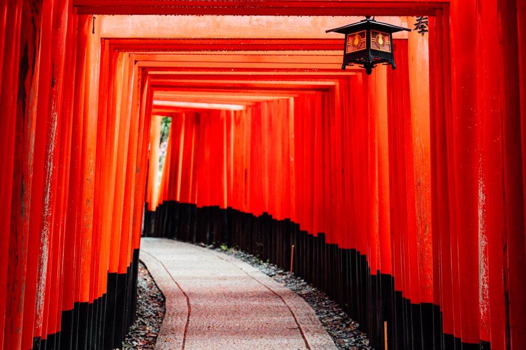 Explore the iconic red torii gates of Fushimi Inari Shrine in Kyoto, Japan, featuring traditional architecture.