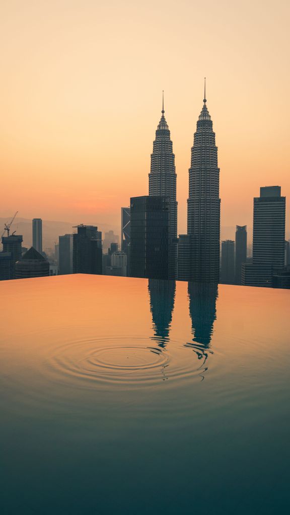 Infinity pool with a breathtaking view of the Petronas Towers at sunset in Kuala Lumpur, Malaysia.